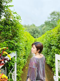 Woman standing by tree against plants