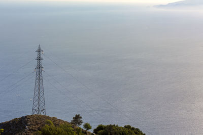 Electricity pylon on mountain against sky