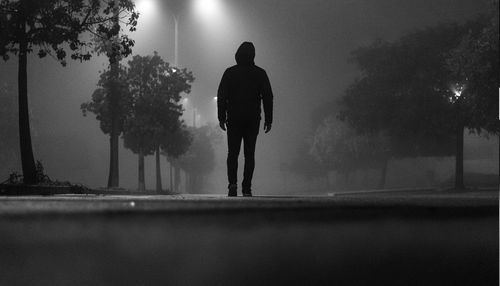 Rear view of silhouette man walking on street at night