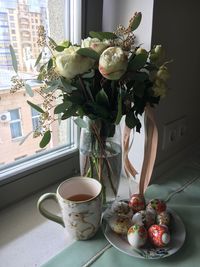 Flower vase on table against window