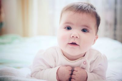 Close-up portrait of cute baby girl in bed