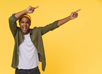 Portrait of young woman standing against yellow background