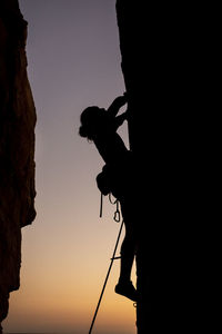 Beautiful view to silhouette of man climbing during sunset