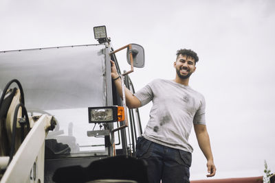 Portrait of happy construction worker standing at doorway of vehicle