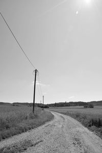 Scenic view of road amidst field against sky