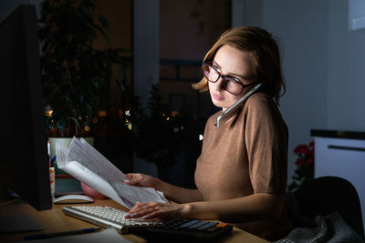 Businesswoman using mobile phone while working at home