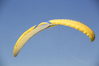 Closeup of a single yellow paraglider with blue sky