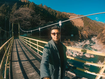 Portrait of young man standing on footbridge