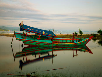 Fishing boats moored on sea against sky