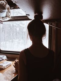 Rear view of woman sitting on table at home