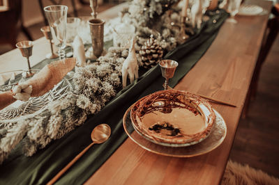 Style christmas table setting, gold plate and cutlery, on a wooden table and green cloth
