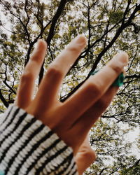 Low angle view of woman feet on tree against sky