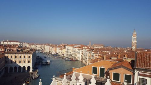 High angle view of buildings by canal against clear sky