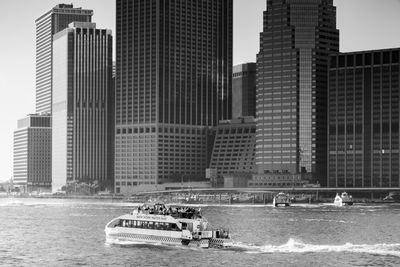 New york city water taxi zooming up the east river alongside lower manhattan in black and white.