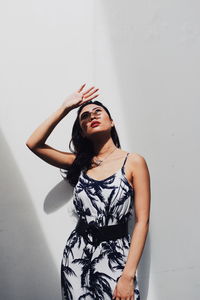 Young woman standing against wall