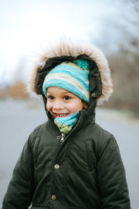 Smiling boy wearing warm clothes looking away while standing outdoors