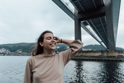 Portrait of young woman standing against river