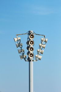 Low angle view of speakers against blue sky