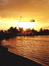 Silhouette sailboats in river against sky during sunset