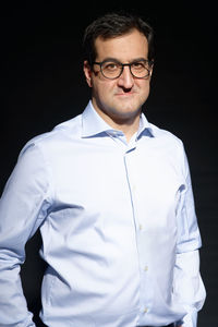 Man wearing hat standing against black background