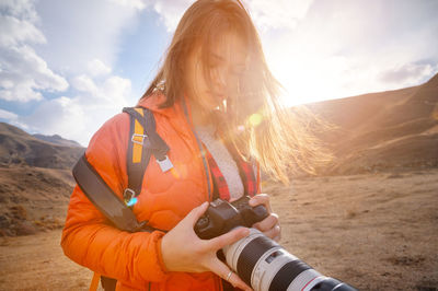 Young hipster woman with a camera in her hands in the mountains in backlight. hair fluttering