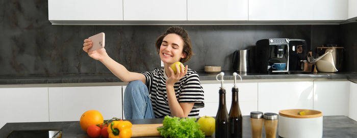 Portrait of young woman using mobile phone while sitting at home