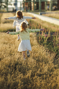 Happy girls with arms outstretched walking on grass