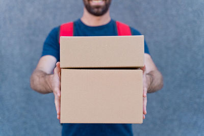 Midsection of man holding paper while standing against wall