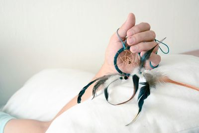 Cropped hand holding dreamcather on bed