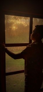 Rear view of boy looking through window