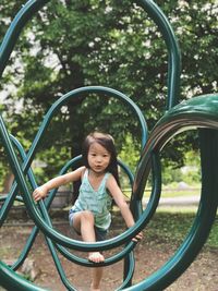 Portrait of girl climbing on green play equipment at playground