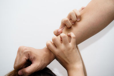 Close-up of hand holding hands over white background