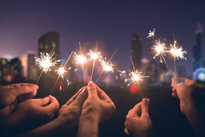 Cropped hand holding sparkler at night