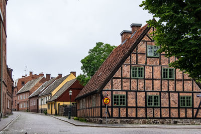 Houses by street amidst buildings against sky