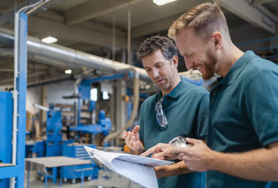 Two carpenters standing and talking in production hall