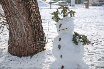 Snowman by tree on field