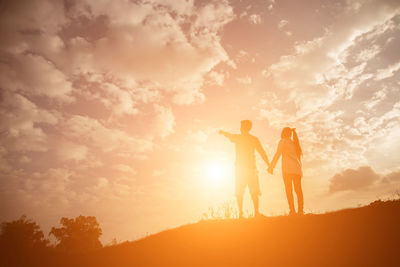 Silhouette friends standing against sky during sunset