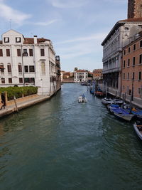 Canal amidst buildings in city against sky