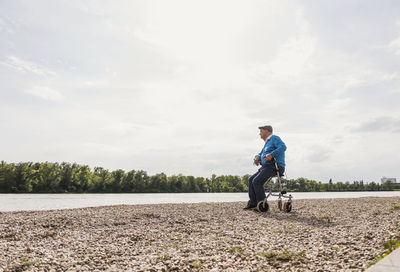 Senior man sitting on wheeled walker at riverside