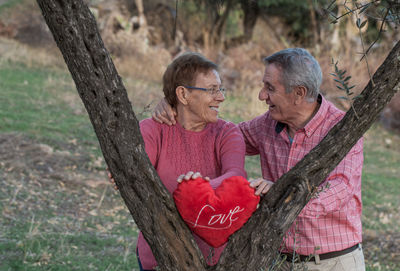 Man and woman standing by tree trunk