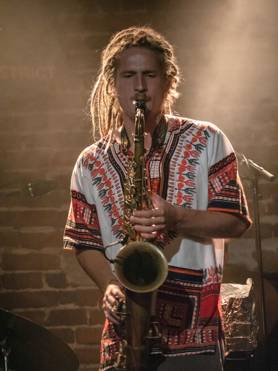 holding, one person, young adult, real people, musical instrument, music, casual clothing, front view, young men, wind instrument, performance, musician, arts culture and entertainment, indoors, standing, lifestyles, skill, three quarter length, saxophone, trumpet
