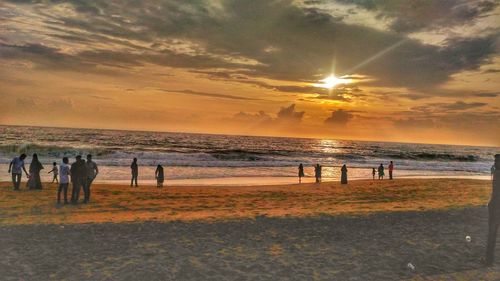 People on beach against sky during sunset