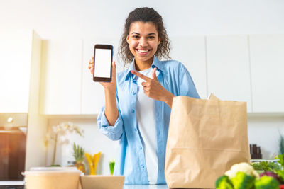 Young woman using mobile phone while sitting on table