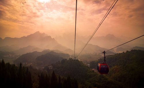 Overhead cable cars over mountains against sky