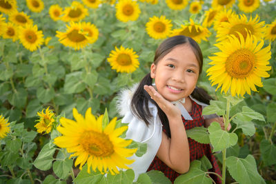 Portrait of smiling girl by sunflower plants