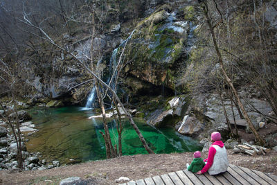 Woman sitting on rock by stream