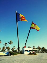 Low angle view of flag on beach against clear blue sky