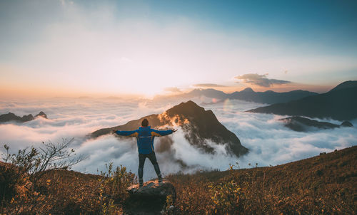 Man standing on mountain against sky during sunset