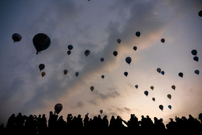 Low angle view of silhouette people flying against sky