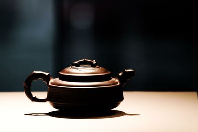 Close-up of teapot on table against wall
